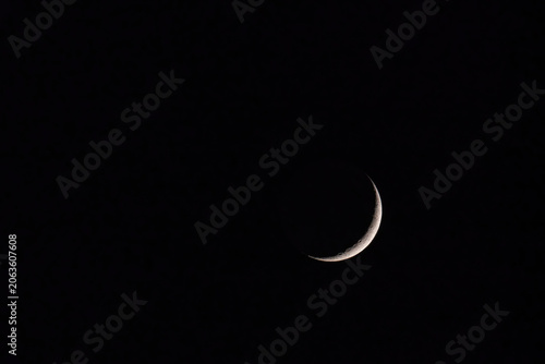Waxing crescent moon with visible craters against dark night sky
