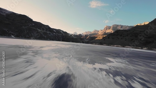 Frozen lake in mountains under clear sky during sunset
