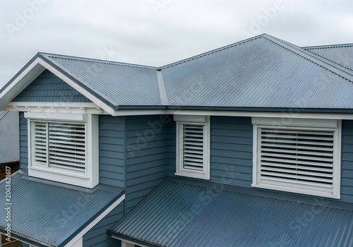 Blue house with white trim and metal roof and cloudy sky