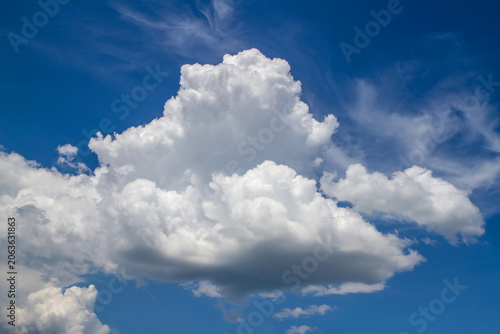 White cumulus cloud against a bright blue sky. Nature background representing freedom, peace and clear weather. Meteorological concept for climate and environment.