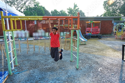 Young boy exercising on playground bars outdoors during active childhood recreation and healthy lifestyle activity.