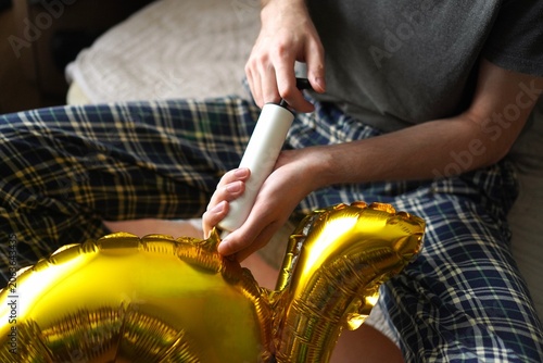 Fotografi Person inflating shiny golden foil balloon using a hand pump on a soft surface