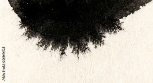 Abstract black ink bleeding on textured white paper background