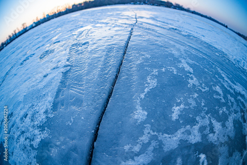 Fotografie Top view of a river covered in ice, divided by a vertical seam into two symmetri