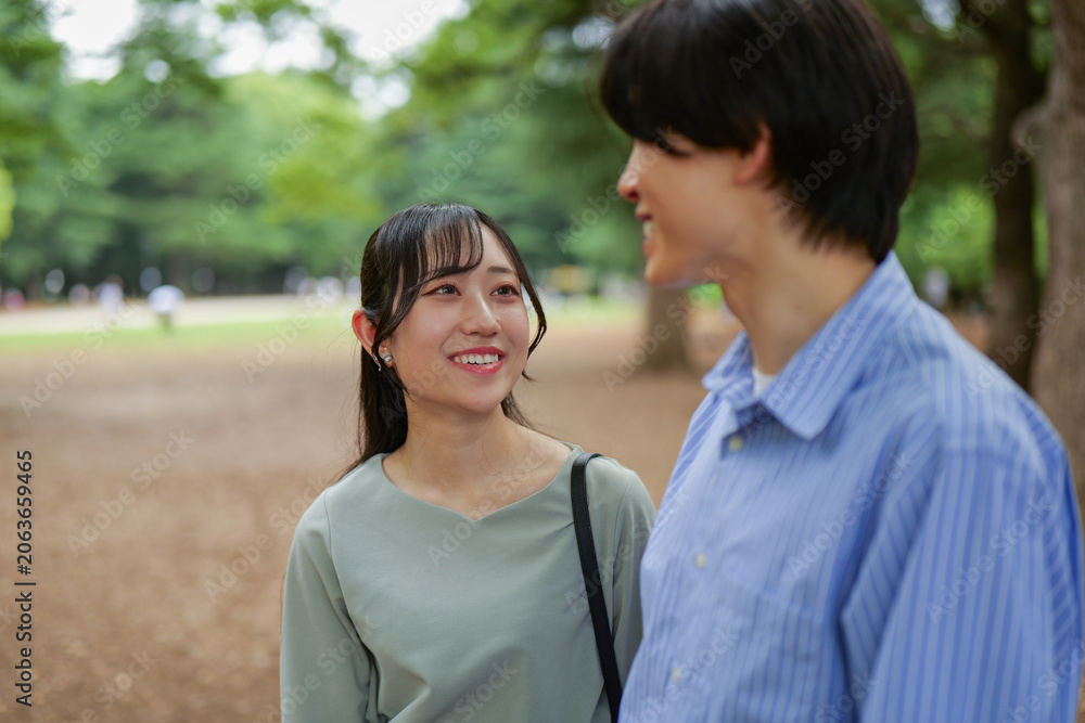 Obraz premium 新緑の公園で話をする笑顔のカップル