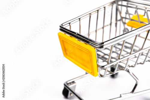 Obraz na plátně Red mini cartoon shopping trolley on white background, slightly askew with a yel