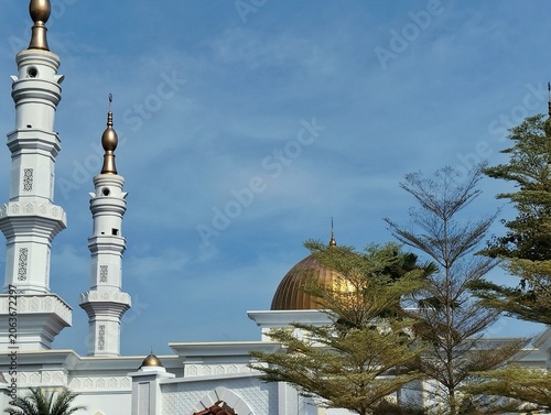 Mosque tower with a serene blue sky background.