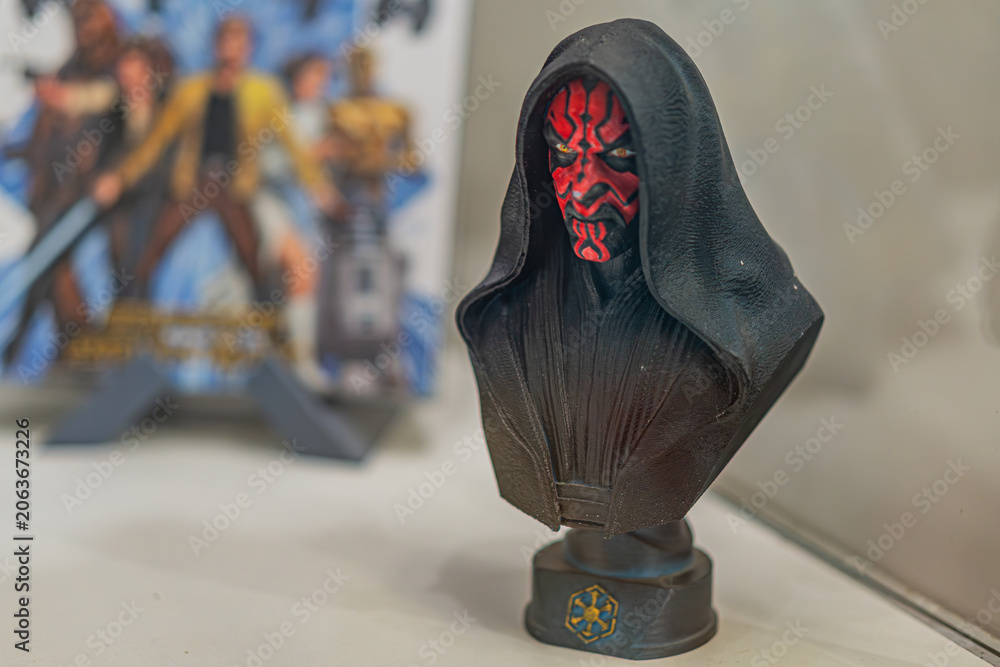Fototapeta premium Close-up image of a black and red Darth Moul bust from Star Wars, against a light gray background Two Star Wars books Princess Leia, C-3PO nearby Focused lighti - Kyiv, Ukraine - September 27, 2025