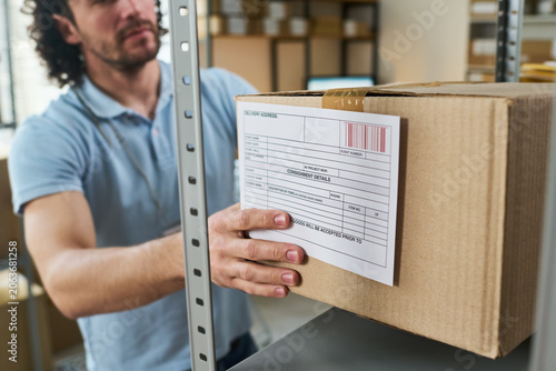 Cuadro en lienzo Young man handling labeled parcel at order pickup point, managing inventory and delivery workflow