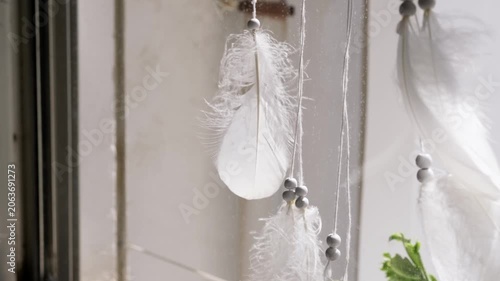 Relaxing scene of a dreamcatcher hanging in a sunny window overlooking the city.