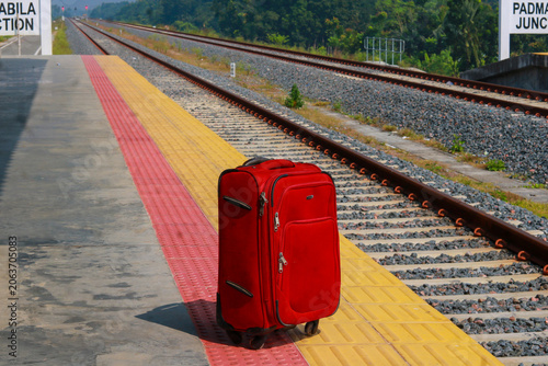 Red luggage suitcase on a railway platform at Junction station.