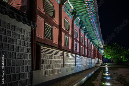 Bild auf Leinwand Beautiful night view of illuminated traditional stone wall and wooden corridor a