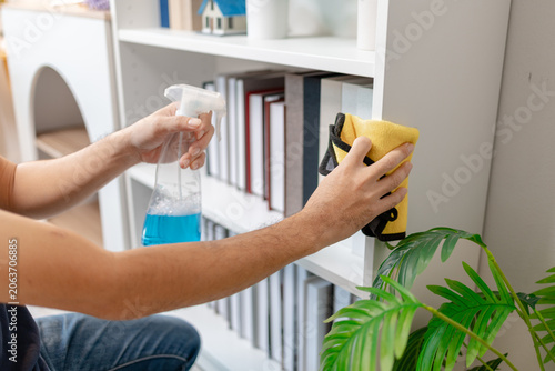 Obraz na plátne Professional home and office cleaning with disinfecting spray, wiping shelves, dusting furniture and sanitizing sofa surfaces to maintain a clean, organized and healthy indoor environment