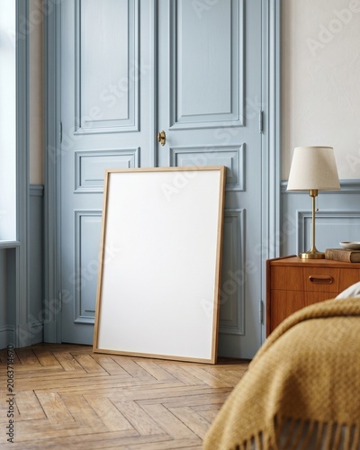 Blank wood frame mockup leaning on parquet floor next to pastel blue vintage wardrobe