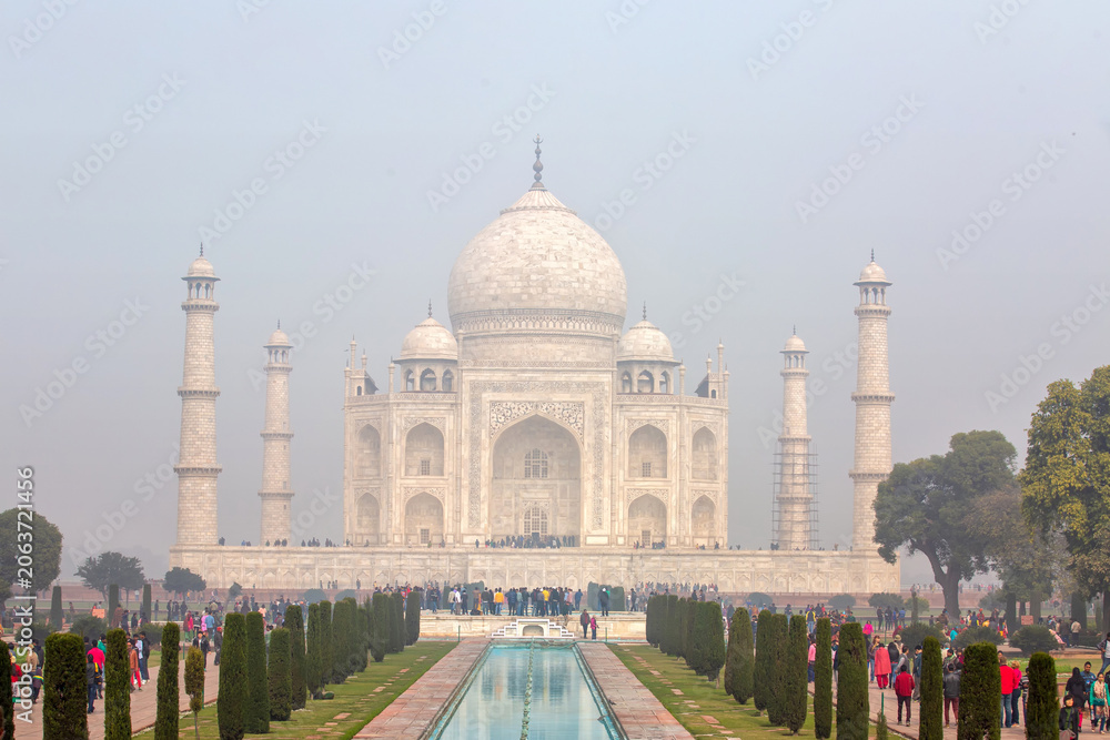 Obraz premium Beautiful front view of Taj Mahal mausoleum with the water fountain channel and crowds of tourists in Agra India Famous UNESCO world heritage site
