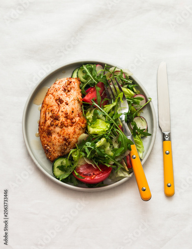 Healthy diet, balanced lunch - baked chicken breast and fresh vegetable salad on a light background, top view