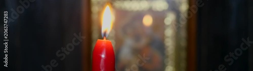 Burning candle providing spiritual light against a blurred religious icon Symbolizing faith hope remembrance and devotion.
