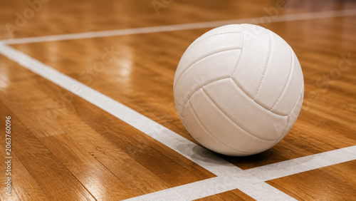 White volleyball resting on the polished wooden floor of an indoor sports court