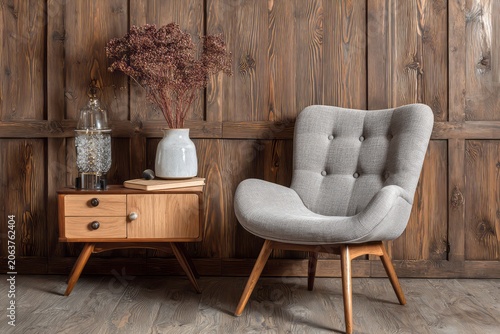 Gray upholstered armchair and side table with decor against wood paneling.
