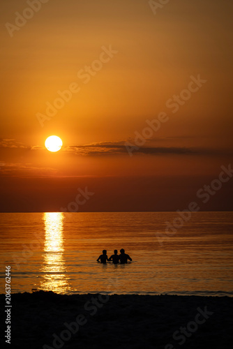 Three friends in the sea at sunset