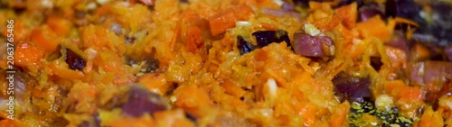 Cooking fresh chopped carrots purple onions and garlic close up in a pan preparing a nutritious and tasty dish.