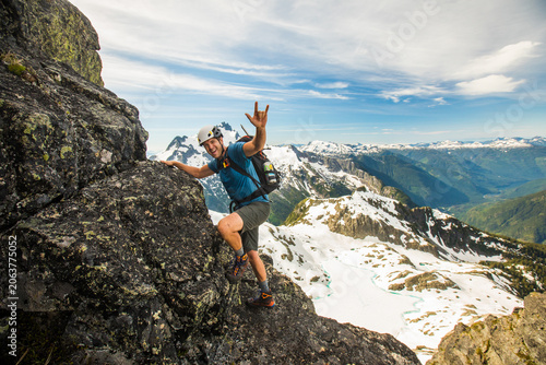 Happy hiker scrambles up a rocky mountain peak