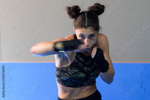 Determined female fighter practicing sharp punches during highenergy workout session inside gym