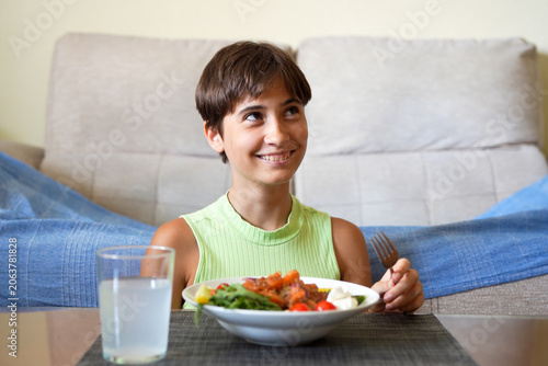 Happy kid dining. Joyful young child savoring fresh vegetables in bright kitchen setting