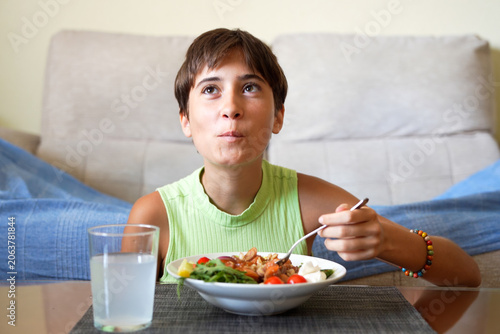 Playful young child enthusiastically relishes crunchy salad with bright eyes and cheerful demeanor