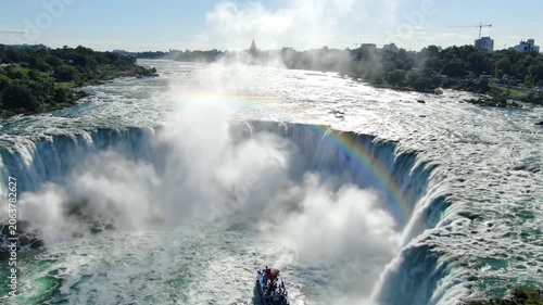Breathtaking Aerial View of a Majestic Waterfall Surrounded by Lush Greenery and a Vibrant Rainbow Stretching Over the Cascading Waters.