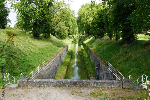 View from the entrance to the 3.333-meter-long Burgundy Canal Tunnel (Canal de Bourgogne tunnel) from 1832 at Pouilly-en-Auxois. Path, trees, bridge. June, summer, France.