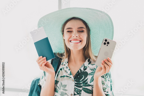 Cheerful young woman with travel essentials including a phone and passport ready for her exciting summer adventure