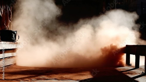 Dust cloud billows across a red dirt floor in a dark, mysterious interior space