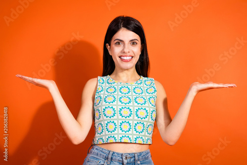 Fényképezés Young woman with a bright expression posing with hands out against vibrant orang