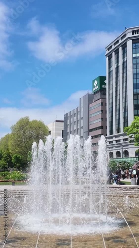 Fountains spraying water in a Japanese city park - Vertical video