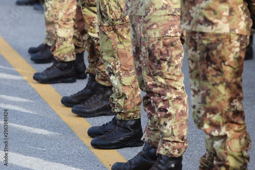 Close-up of soldiers' legs in military camouflage pants and black combat boots standing in formation