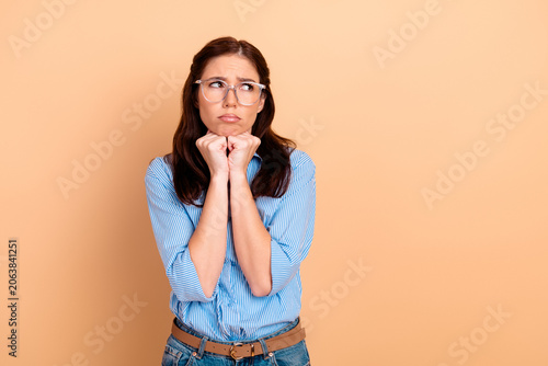 Quadro su tela Young woman looking worried and pleading with clasped hands, wearing glasses and
