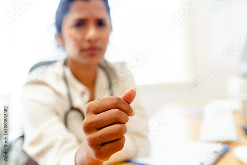 Female medical practitioner extending her hand forward with her fingers curled inward