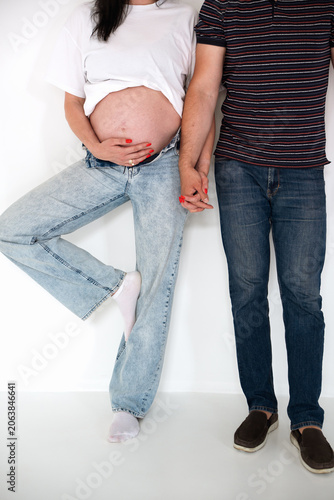 Pregnant Couple Holding Hands Standing Against White Background