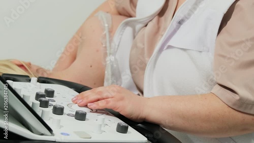 Healthcare worker operates control panel near man during diagnostic recording. Nurse adjusts buttons managing machine settings for cardiac test