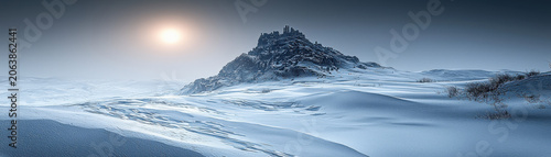 Majestic mountain peak in vast winter snow landscape. cold light from sun illuminates serene scene
