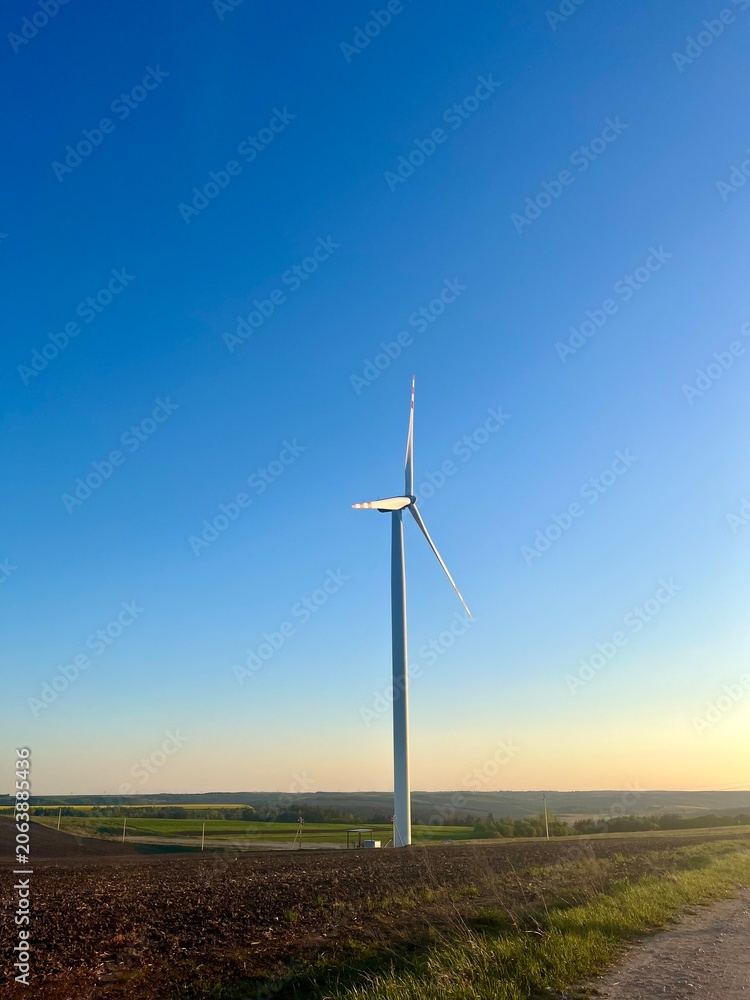 Fototapeta premium wind turbine in the green field in sunset view