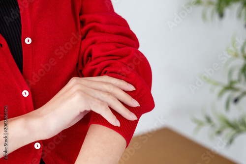 Woman Rolling Up Sleeves of Red Cardigan