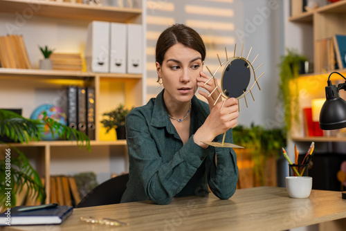 Foto Young woman on home table enjoys mirror reflection smiles with joy during beauty self care break