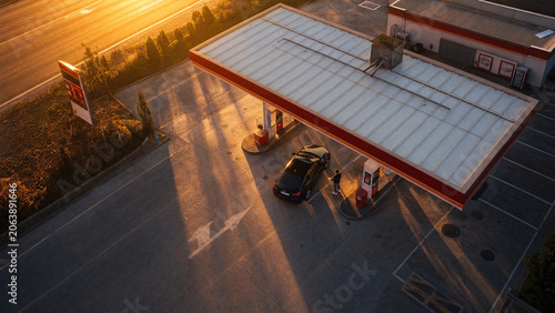 Refuel fuel gasstation pump car receipt keys driver payment sunset scene showing a driver holding receipt and car keys beside a pump during golden hour with warm light and blurred road background
