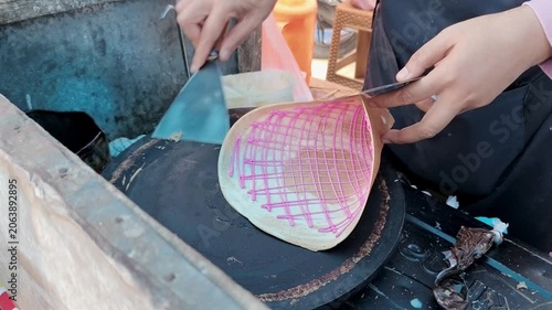 Hands are lifting a crispy, thin crepe from a hot griddle.