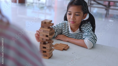 Photos Cute Asian girl child covering eyes playfully during indoor activity to build strong mind intelligence
