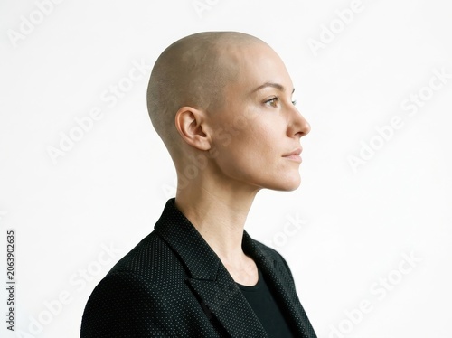 Side profile of a woman with a shaved head wearing a black blazer isolated on white background
