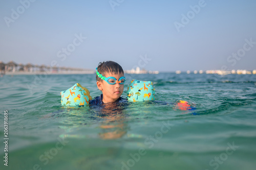Four-Year-Old Multiracial Boy Swimming in Ocean with Floaties an
