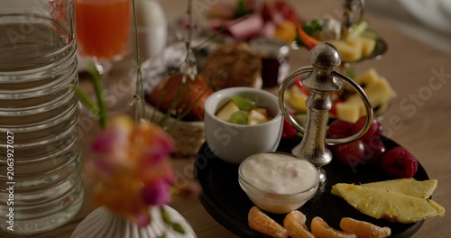 Assorted healthy breakfast with fresh fruits, yogurt, and juice. Features pineapple, tangerine, and apple slices alongside other delicious ingredients. Ideal for nutritious and balanced diet concepts.